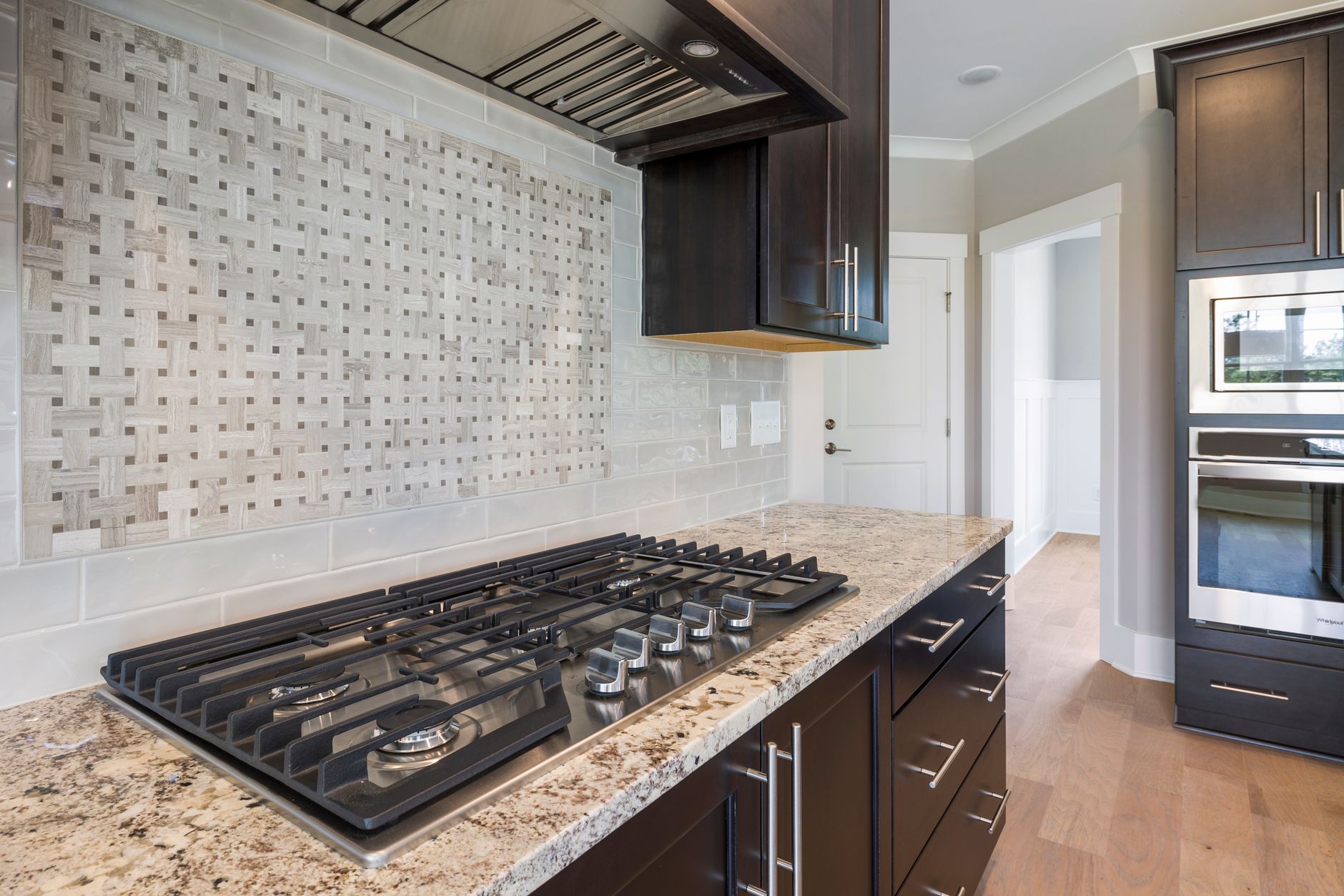 Contemporary kitchen featuring a sleek granite countertop, integrated oven, and stylish backsplash in Riverside, CA